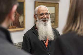 A male employee smiles at visitors in the gallery