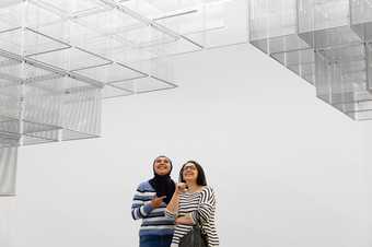 Two people looking up at wire boxes