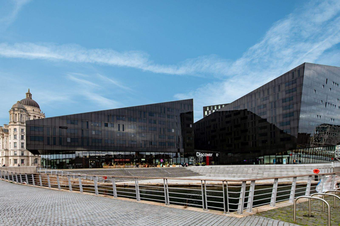 A photograph of the exterior of the Mann Island complex which features two giant black buildings and the word 'Discover' written above the door.